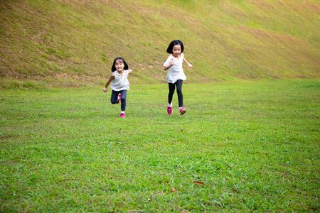 Asian Little Chinese Sisters running happily at the outdoor parkの写真素材