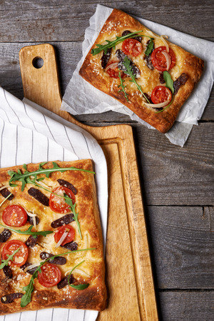 rectangular pizza with salami, tomatoes and rucola leavesの写真素材