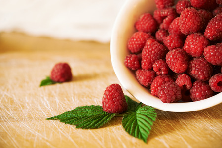 bowl with ripe rasberry on wooden background
