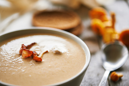 plate of cream soup with chanterelle and bacon on rustic wooden table.  close upの写真素材