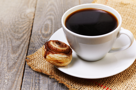 cup of coffee and cinamon bun on wooden tableの写真素材