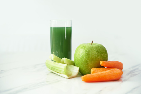 healthy drink glass, carrots, apple and celery on marvle backgroundの写真素材
