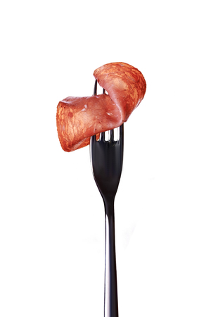 slice of meat on silver fork isolated on white backgroundの写真素材