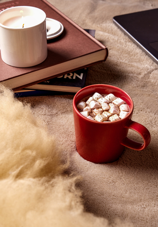 cozy sitting place, mug with marshmallow and candleの写真素材