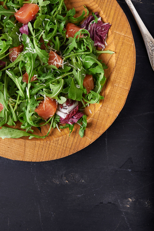 salad with rocket and salmon fish in wooden background. top viewの写真素材