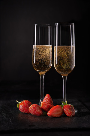 two glass with champagne and strawberries over dark backgroundの写真素材
