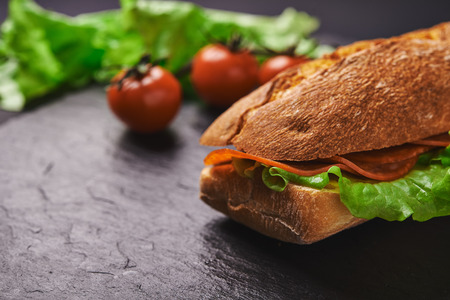 sandwich with pepperoni and lettuce on stone backgroundの写真素材
