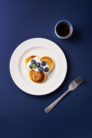 cottage cheese pancakes with blueberries and cup of black coffee. top viewの写真素材