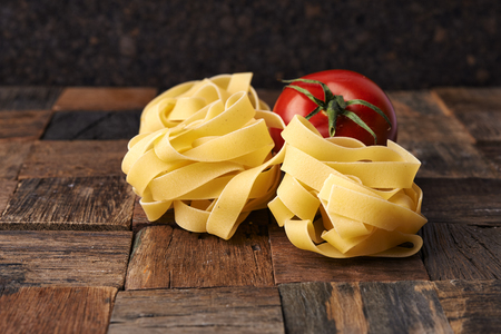 raw fettuccini and fresh tomatoes on wooden tableの写真素材