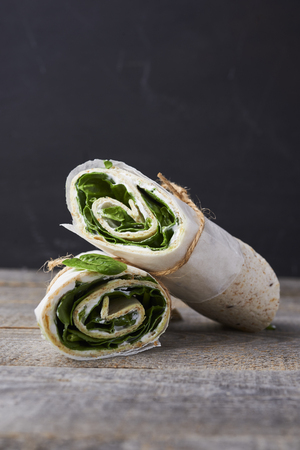 wrapped sandwiches with spinach and cream cheese on wooden backgroundの写真素材
