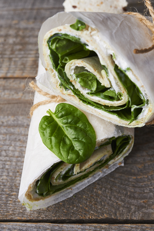 wrapped sandwiches with spinach and cream cheese on wooden backgroundの写真素材