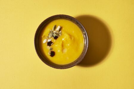 bowl with creamy pumpkin soup on yellow backgroundの写真素材