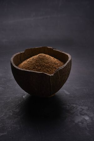 half of coconut's shell  with coconut sugar on dark backgroundの写真素材