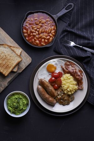 full english breakfast with eggs, sausages, potato, beans, bacon, mushroomsの写真素材