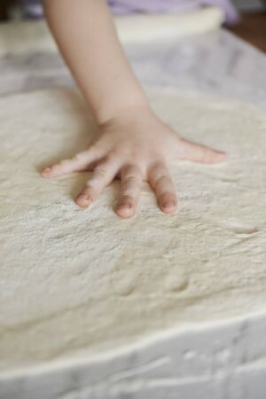 dough for pizza and kid's hands