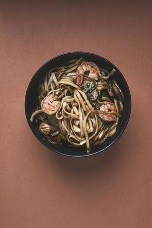 noodles with shrimps and vegetables in black bowl on dark background. top viewの写真素材
