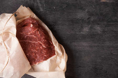 fresh beef in wrapped paper. top view, place for text
