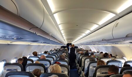 Passengers in a flying airplane of the A320 company Lufthansa and a stewardess offering drinks. April 25, 2019.のeditorial素材