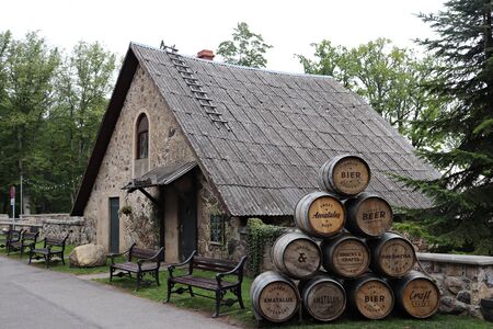 Stone small house and a pyramid of beer barrels on the territory of Sigulda Castle in Latvia. July...