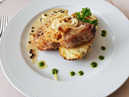 Braised two slices of pork baked potato on a white plateの写真素材