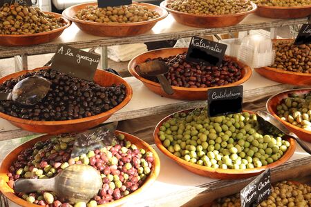 Different varieties of healthy olives in basins on a street market counter.の写真素材