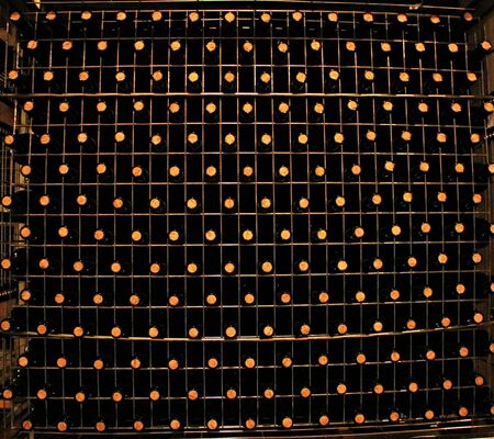 Rows of wine bottles with corks are horizontally stored on racks in a special basement.