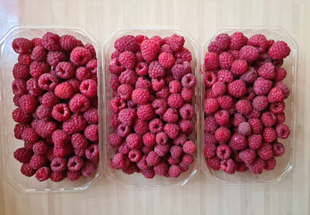 Ripe tasty and healthy raspberries are packaged in small plastic boxes