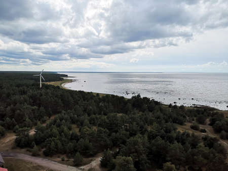 Lone wind generator among the trees on the seaside on a cloudy day
