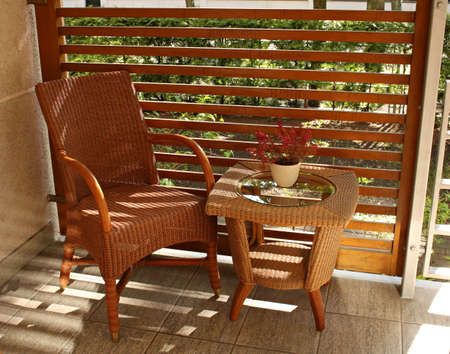 Wicker chair and small sitting table are on the balcony.の写真素材