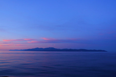 Blue sea against the backdrop of distant mountains in the summer season.の写真素材