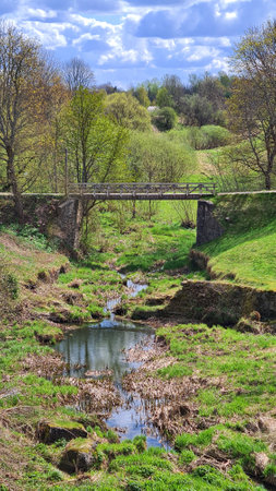 An old small bridge across narrow stream on sunny spring day