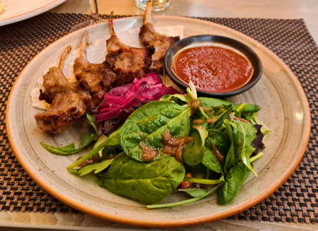Grilled beef ribs served on plate with fresh salad and sauceの写真素材
