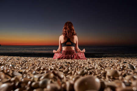 Yoga and meditation on calm beach at sunrise, Young fit womanの写真素材