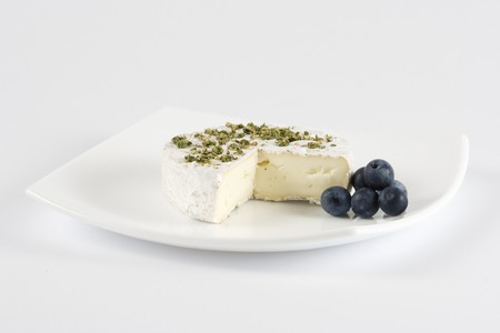 Camembert cheese with green pepper and sloe on white dishの写真素材
