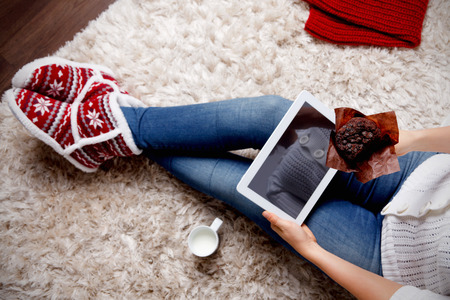 Woman with a tablet eating muffinsの写真素材