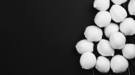 Cotton balls are artistically arranged on a black surface.の素材