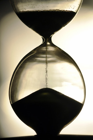 close up hourglass counting down time with moving sand  view vintage silhouette