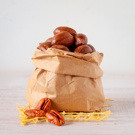 Pecan nuts in a paper bag on wooden tableの写真素材