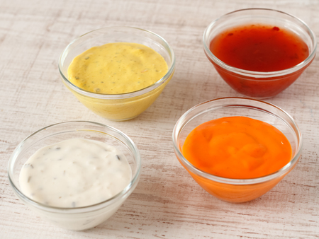 Garlic, chili, curry and cocktail sauce in small bowlsの写真素材