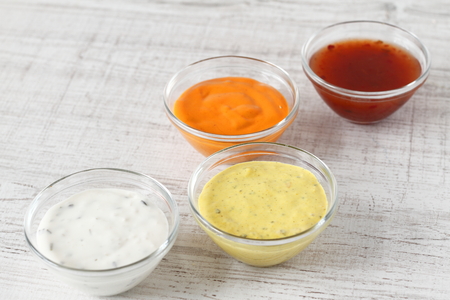 Garlic, chili, curry and cocktail sauce in small bowlsの写真素材