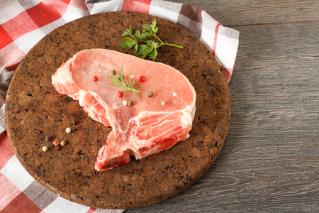 Raw pork steak on dark background with herbsの写真素材
