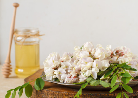 honey with acacia blossoms on a white wooden backgroundの写真素材