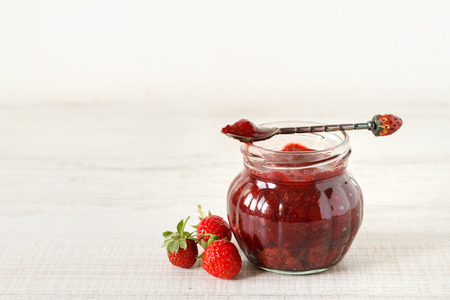 Strawberry jam in a jar on wooden background