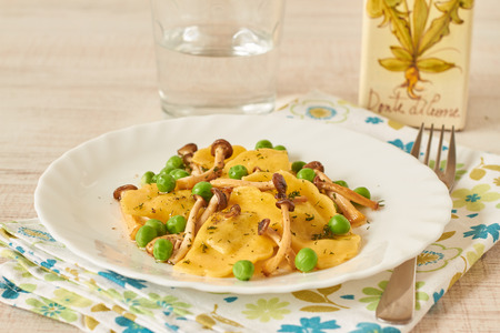 Tortellini with mushrooms and peas on a tableの写真素材