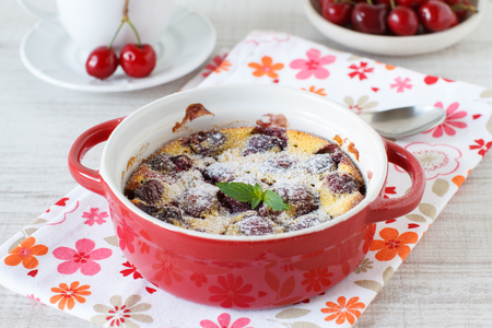 Clafoutis with cherries in red ramekin on wooden backgroundの写真素材