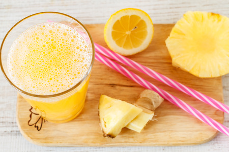 Pineapple,lemon and ginger juice in glassware on wooden table. Top view.の写真素材