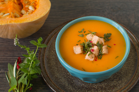 Pumpkin soup with cream and parsley on dark wooden backgroundの写真素材