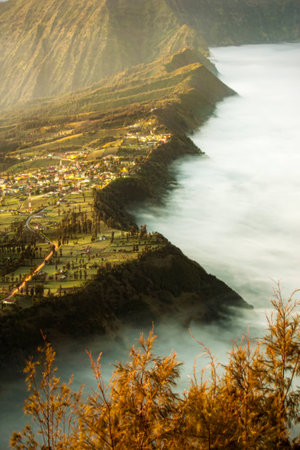 Bromo village on the mountain cliff background with sunrise and foggy landscapeの写真素材