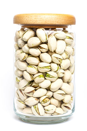 Organic pistachio nut full fill in glass bottle with wood cap on white backgroundの写真素材