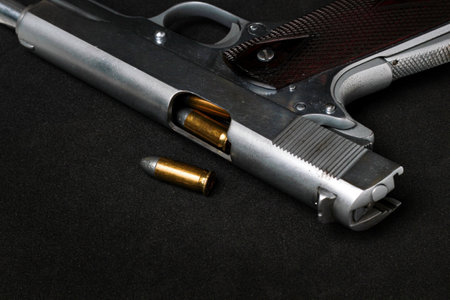 Automatic white gun stainless steel pistol weapon model m1911 with real bullet ammo head in black backgroundの写真素材